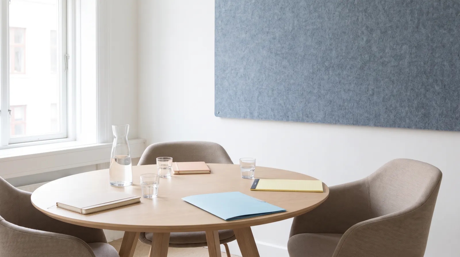 Salle de réunion lumineuse avec une table ronde et trois chaises, prête pour une médiation